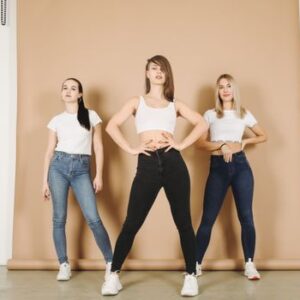 Three women in casual denim outfits posing confidently in a studio setting.